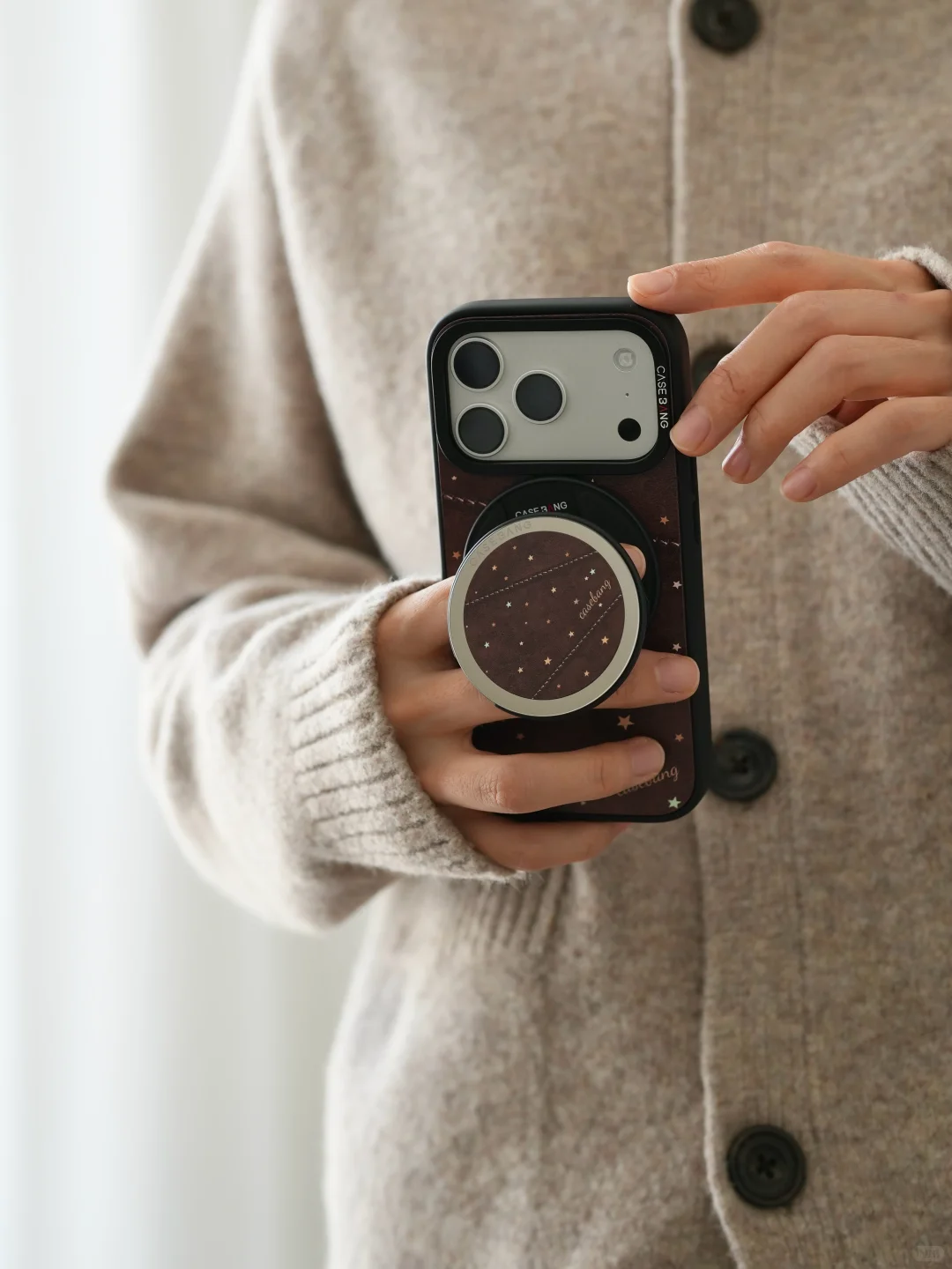 Original real photograph of a star-pattern CaseBang phone case with its round grip, held in two hands.